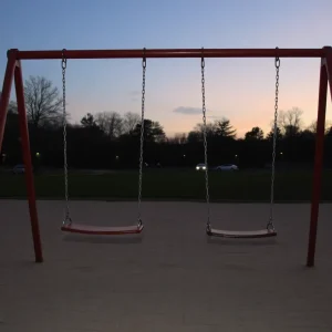 Empty swings in a quiet park at dusk.