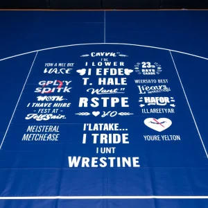 Wrestling mat with inspirational quotes and team spirit symbols.