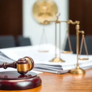 Courtroom gavel with documents and scales of justice.